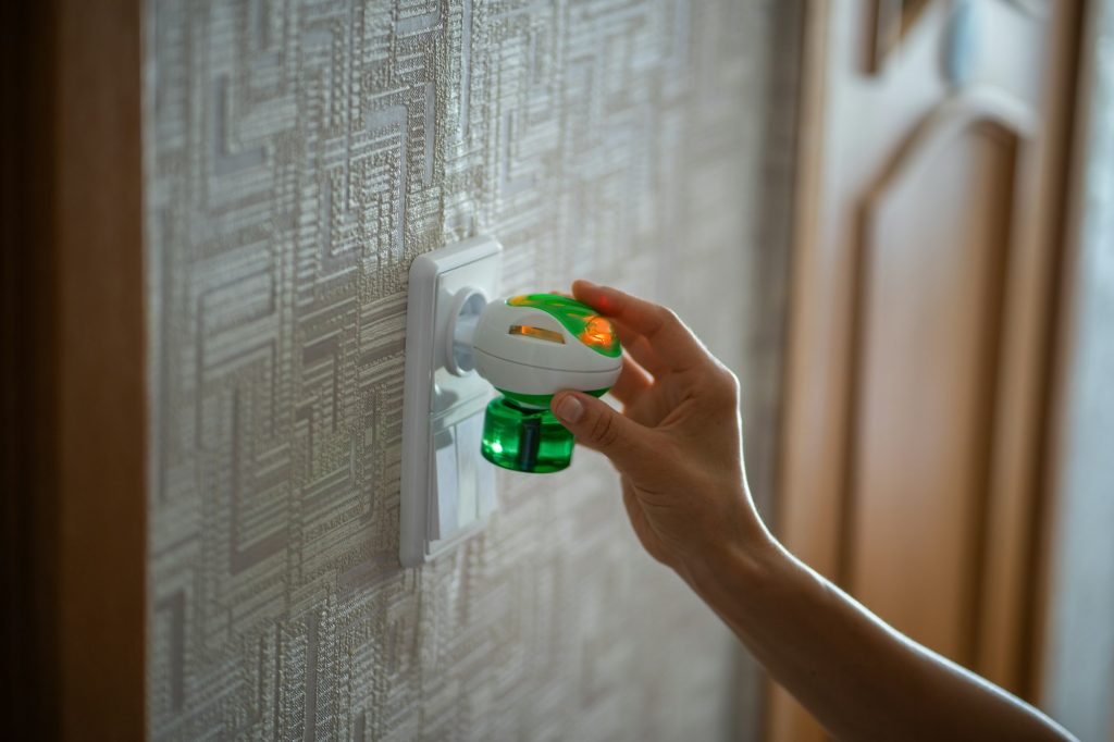 Woman hand plugs mosquito repellent into the socket at home. Electric insect repellent diffuser.