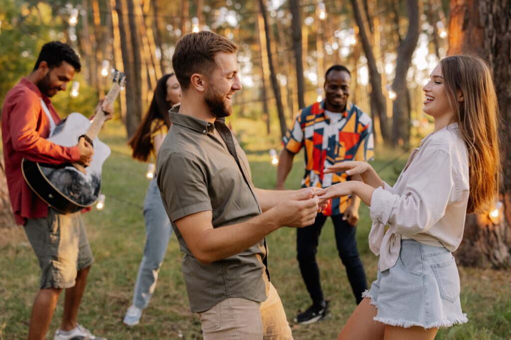 A beautiful couple dancing on the background of friends having fun
