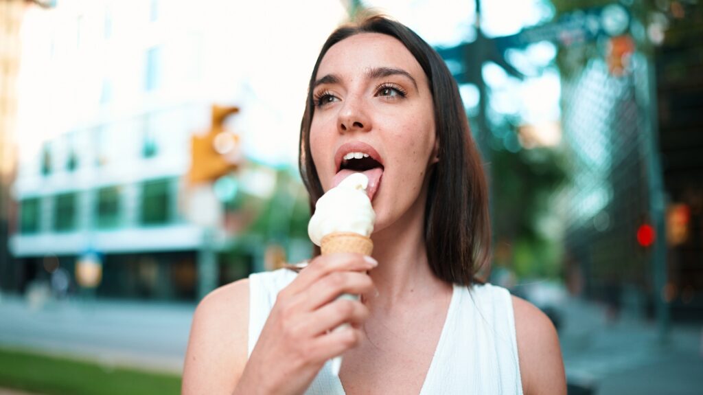 Cute girl enjoys ice cream on modern city background