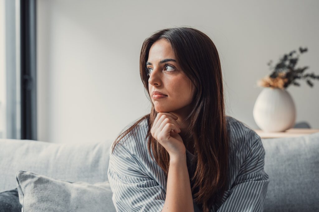 Close up of sad pensive millennial woman sit alone thinking about relationships personal problems
