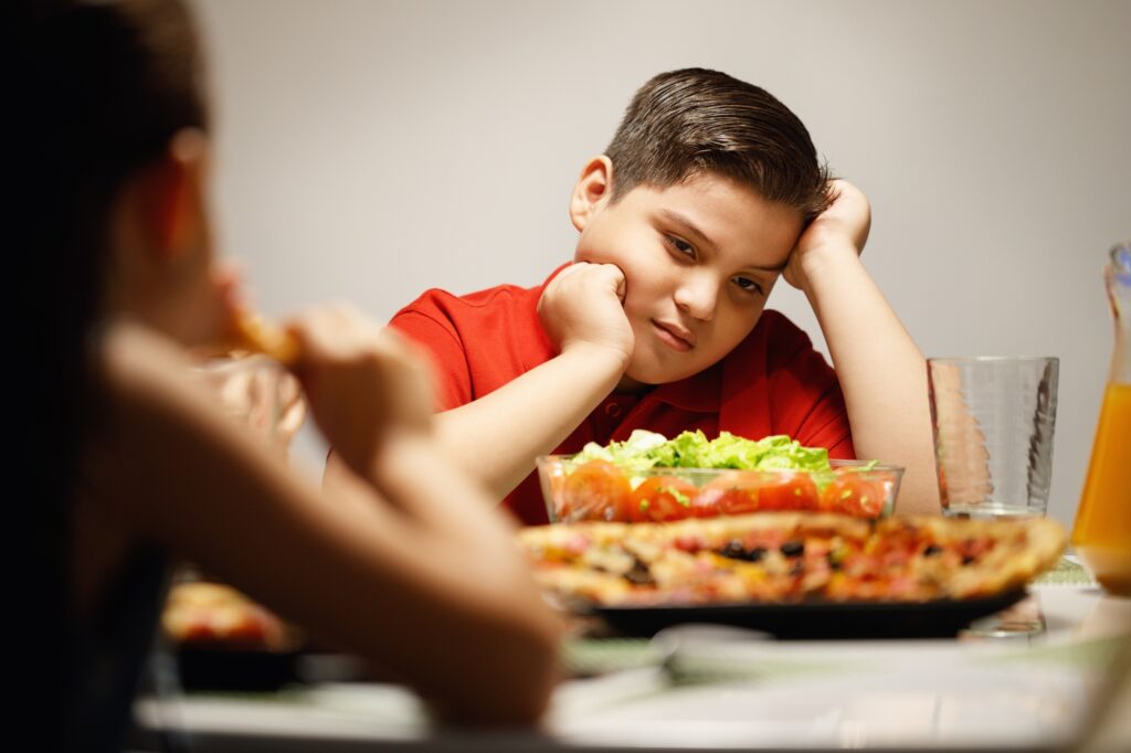 Mother Giving Salad Instead Of Pizza To Overweight Son