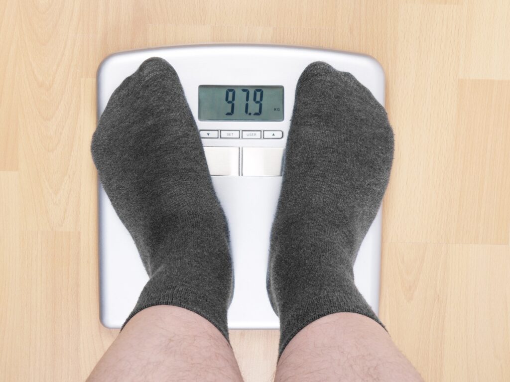 overweight man standing on bathroom scales