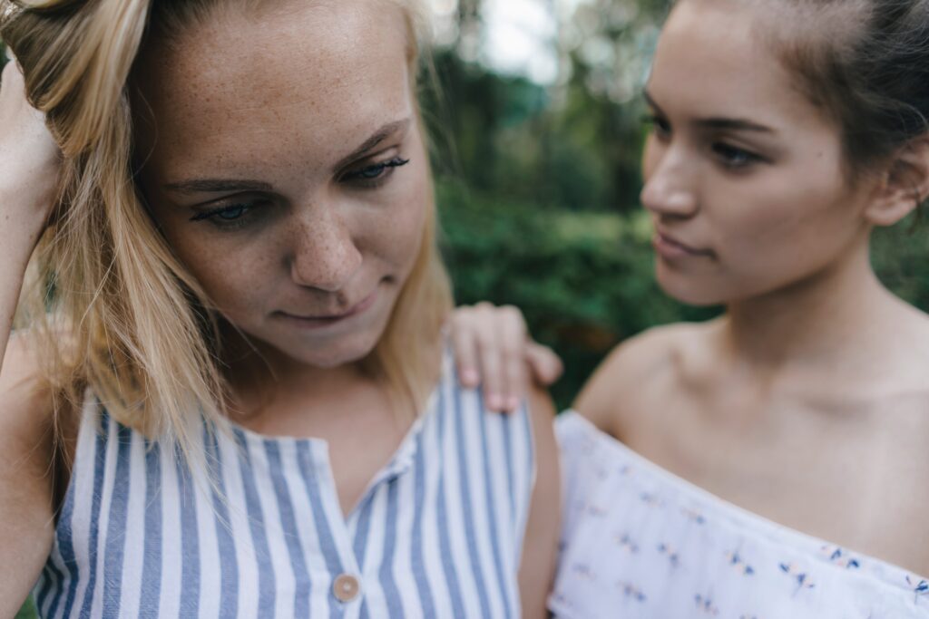 Young woman comforting sad female friend