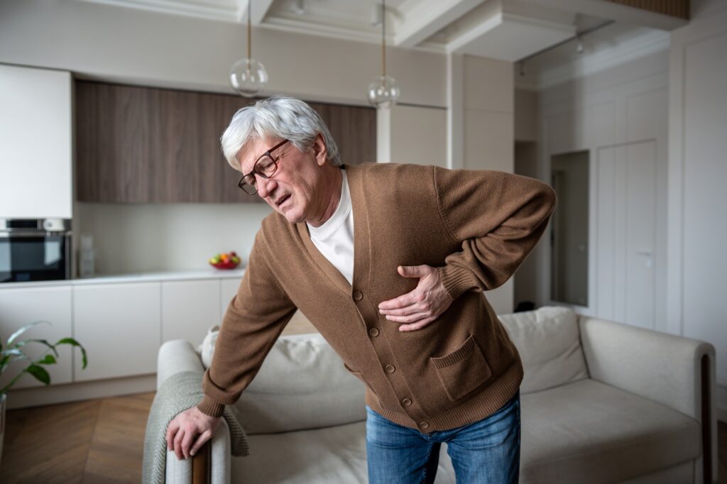 Sudden chest discomfort. Elderly man clutches chest in agony struggling to breathe in heart attack