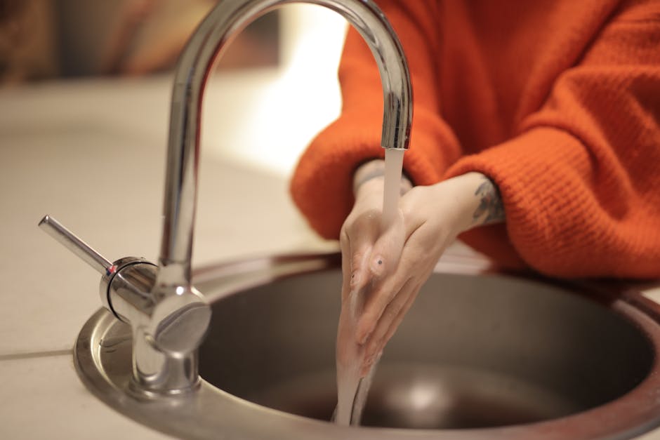 People washing hands in a bathroom sink with soap and water