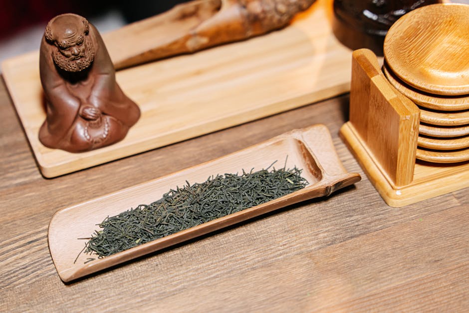 A cup of green tea with fresh tea leaves on a wooden table