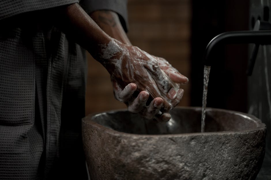 Person washing hands with soap at a bathroom sink