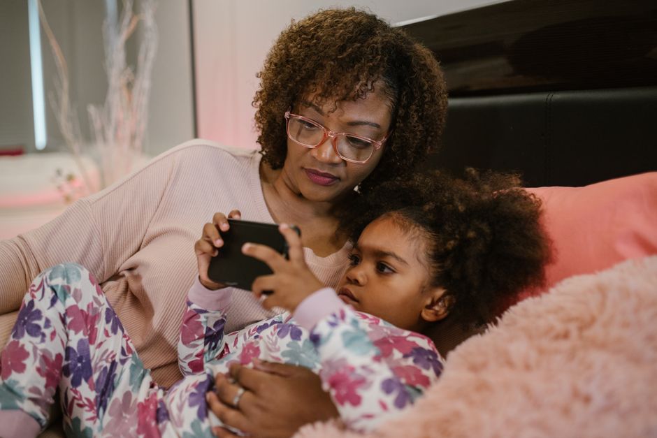 Person using smartphone at home with child in background