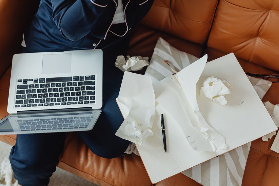 Anxious writer at desk with hands on head and empty notebook