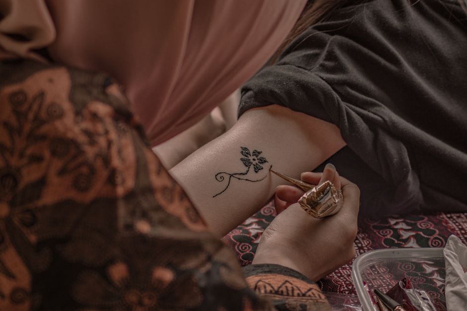 Close-up of natural henna paste being applied in a traditional temporary tattoo pattern