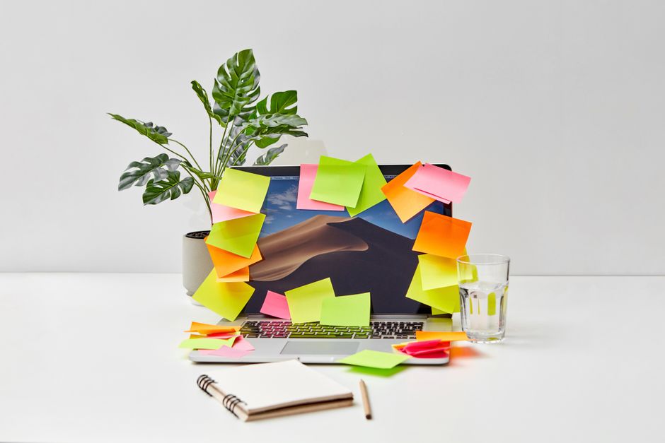 Person overwhelmed at desk with notes and computer, representing writing block