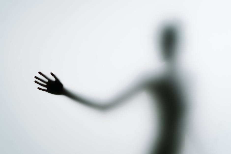 Le corps humain émet-il vraiment de la lumière ? Ce que disent les études récentes Blurred silhouette of a hand reaching out against a light background in an abstract style.