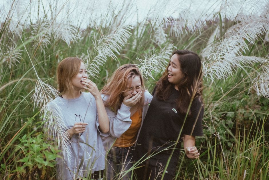 A group of people laughing together in a bright, natural setting
