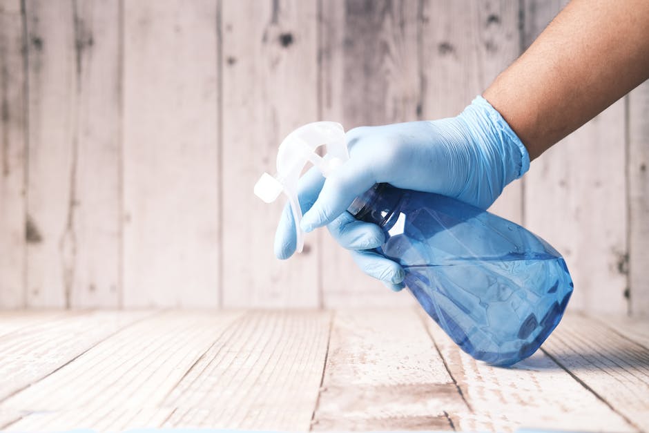 Gloved hands preparing a cleaning solution in a bucket