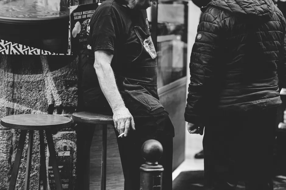 A candid black and white photo capturing street life in Naples, Italy, featuring two adults conversing.