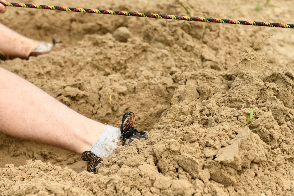 A close-up image of feet partially buried in sandy soil, depicting outdoor adventure.