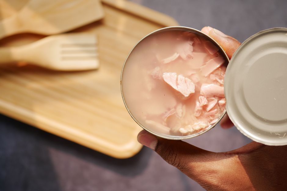 Thon en conserve : le mercure est-il dangereux? A close-up of an opened canned tuna held over a wooden cutting board and utensils.