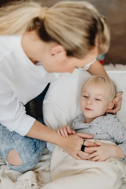 A nurturing mother takes care of her child who is comfortably resting indoors during the day.