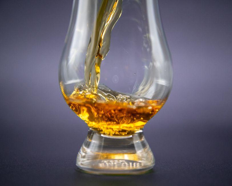 L’eau distillée est-elle vraiment dangereuse à boire? Close-up of golden whiskey being poured into an elegant glass.
