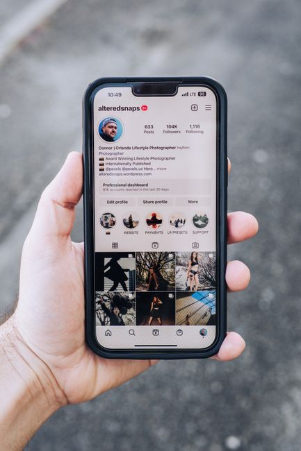 Hand holding a smartphone displaying an Instagram profile screen close-up.