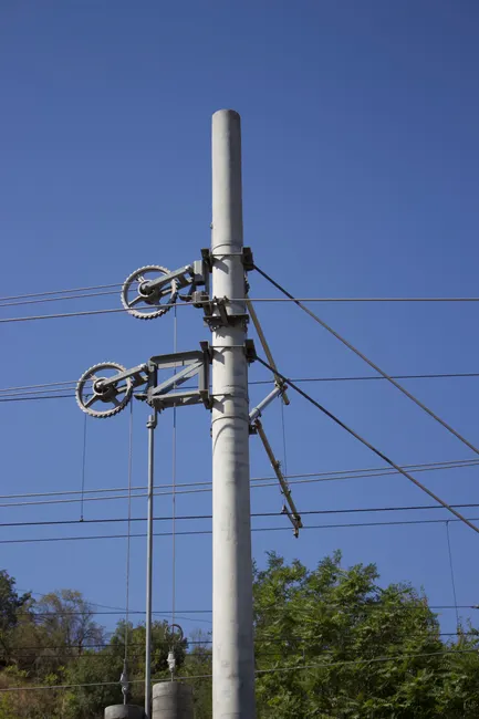 High voltage power line pole with detailed mechanical components under a clear blue sky.