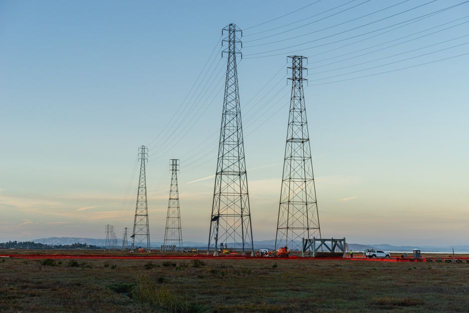Les champs électromagnétiques des lignes à haute tension causent-ils des cancers? High voltage transmission towers with clear blue sky at dusk in an open field.