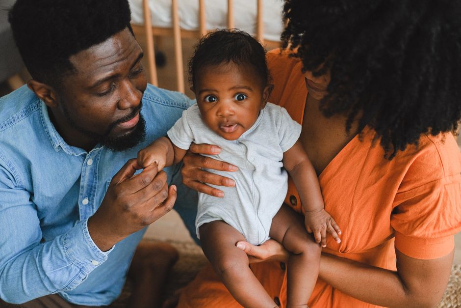 L’effet Mozart existe-t-il vraiment pour les bébés? Loving parents holding adorable baby in a warm, intimate home environment.
