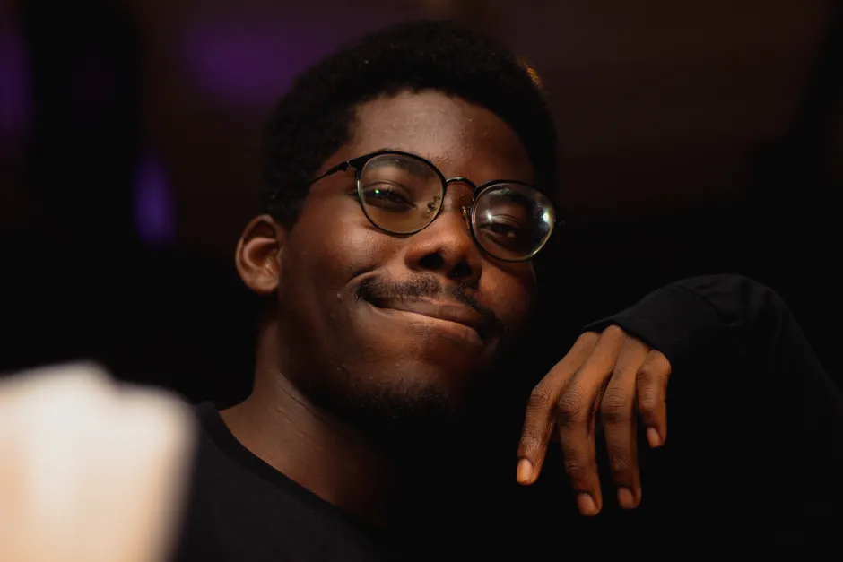 Portrait of a confident adult man with glasses smiling with a hand on his chin.