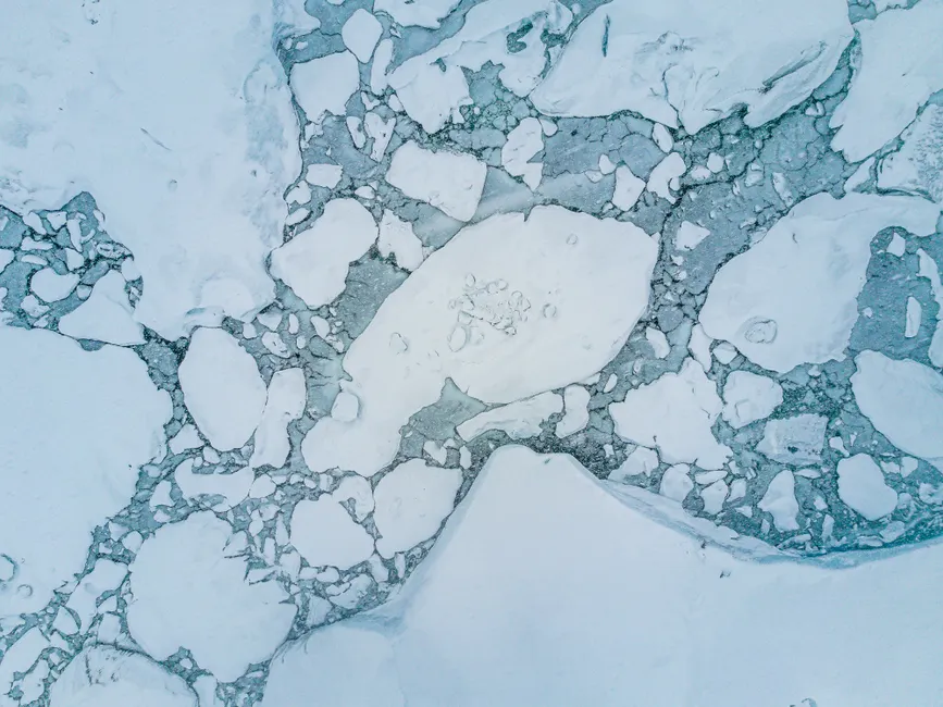 L’Arctique sera-t-il libre de glace d’ici 2050? Stunning aerial shot of icy arctic landscape showcasing floating ice and calm winter sea.