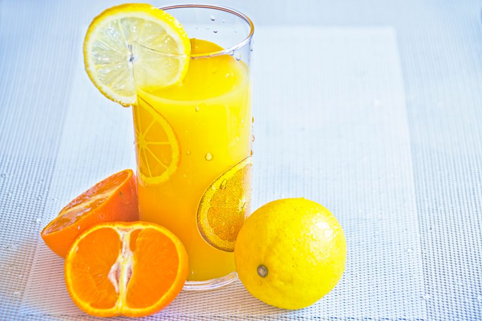 Le citron est-il un aliment alcalinisant malgré son acidité? Vibrant citrus juice in a glass with fresh orange and lemon slices, offering a refreshing taste of summer.