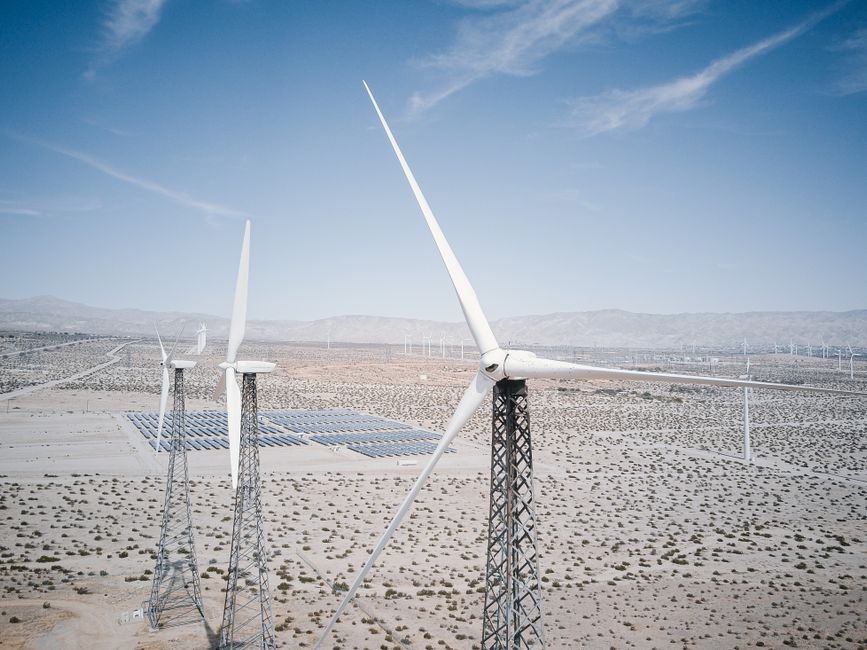 Le monde pourrait-il fonctionner uniquement avec des énergies renouvelables? Wind turbines and solar panels generating renewable energy in a desert landscape.
