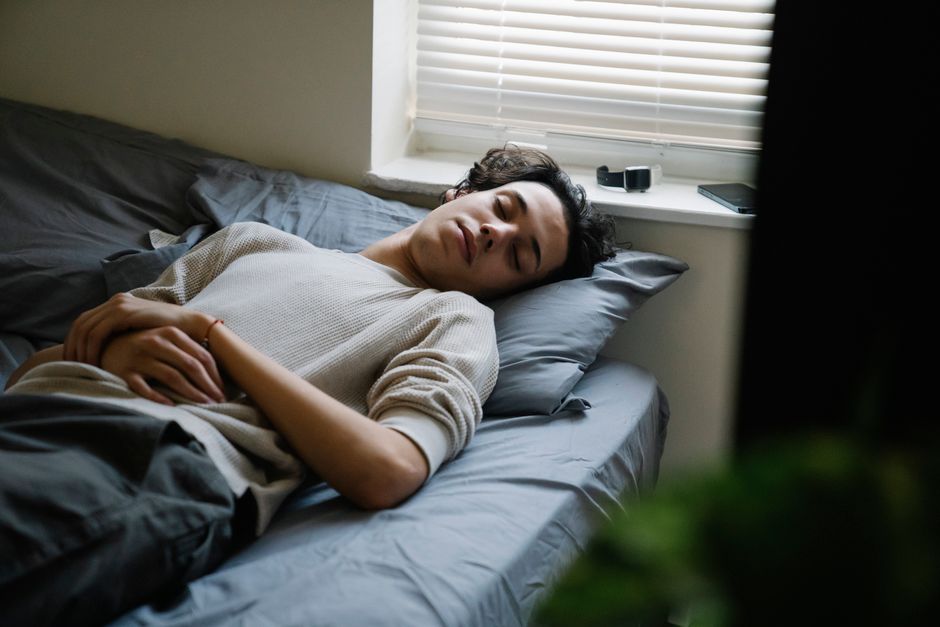 Peut-on vraiment rattraper une nuit blanche? A man calmly sleeps on a bed in a cozy bedroom with soft lighting.