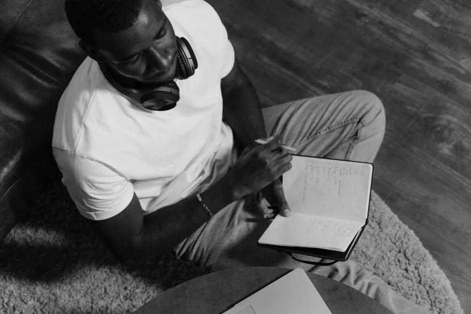 Peut-on vraiment apprendre pendant son sommeil? Le verdict A man takes notes in a notebook while sitting indoors, using headphones for an online class.