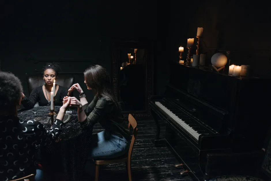 A mysterious group seance in a dimly lit room with candles and a piano, evoking spiritualism.