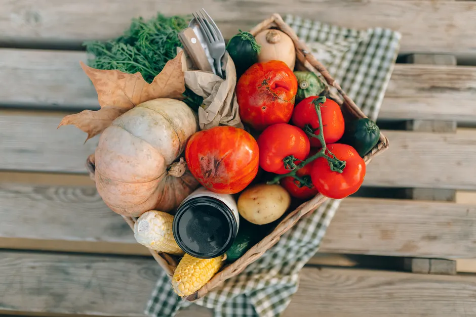 Les aliments bio sont-ils vraiment plus nutritifs? Le verdict des études A top-down view of a basket filled with fresh vegetables and produce, placed on a wooden table.