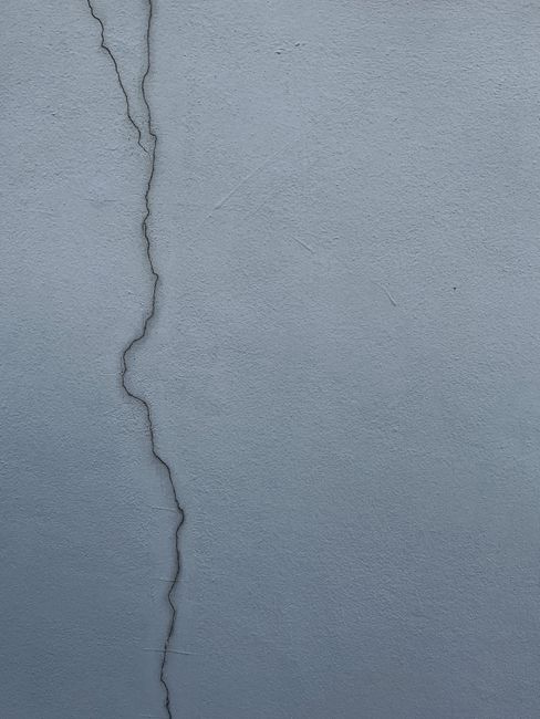 Close-up of a cracked cement wall displaying texture and structural detail.
