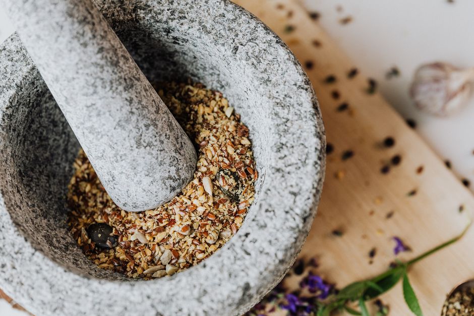 Les momies égyptiennes étaient-elles vraiment réduites en poudre comme remède? Close-up of ground spices in a stone mortar and pestle on a wooden board.