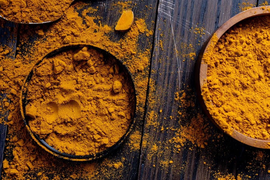 Le curcuma est-il vraiment efficace contre l’inflammation? Close-up of turmeric powder in rustic bowls on a wooden surface, ideal for spice and food photography.