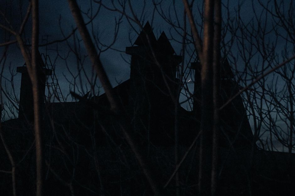 Les maisons hantées ont-elles vraiment une explication scientifique? Eerie shadow of an old house seen through leafless trees under a crescent moon night sky.