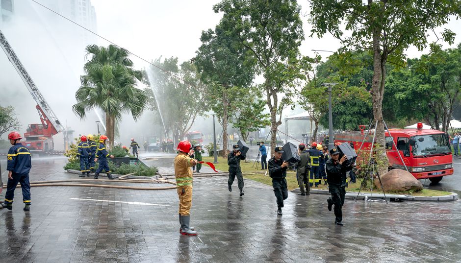 Firefighters and rescuers in action controlling a fire outdoors, using hoses.