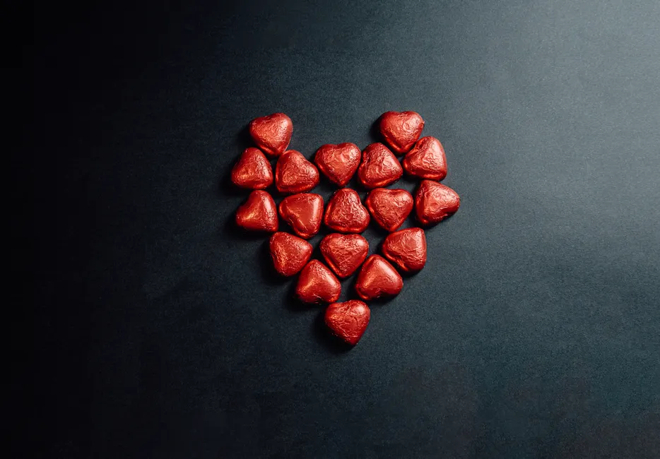 Le chocolat noir est-il vraiment bon pour le cœur? Heart-shaped chocolates arranged on a dark surface, perfect for love and romance themes.
