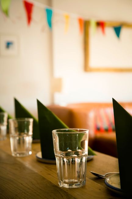Indoors festive table setting with glasses, napkins, and colorful bunting decorations.