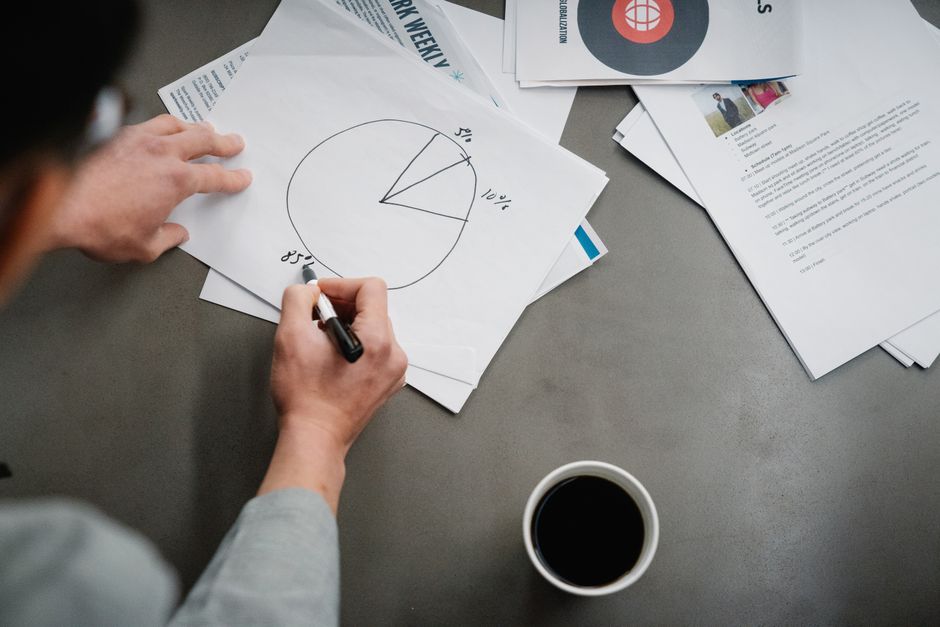 Le QI moyen de l’humanité augmente-t-il vraiment à chaque génération? Man drawing a pie chart on paper with coffee, representing business planning and analysis.
