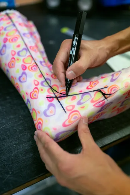 Orthotic technician tracing design on colorful ankle foot brace.
