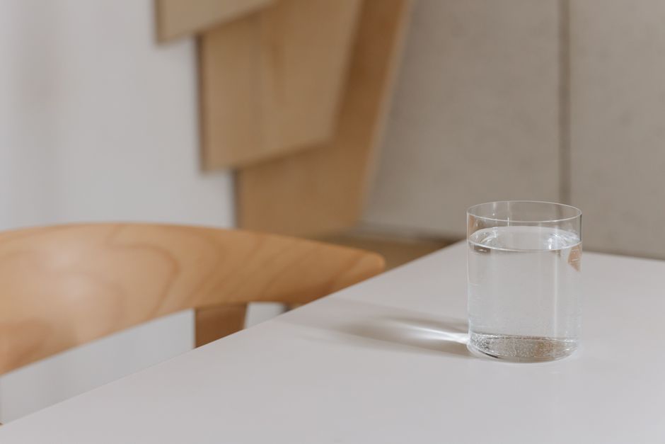 Boire huit verres d’eau par jour est-il vraiment indispensable? Simple and elegant composition of a water glass on a modern wooden table indoors.