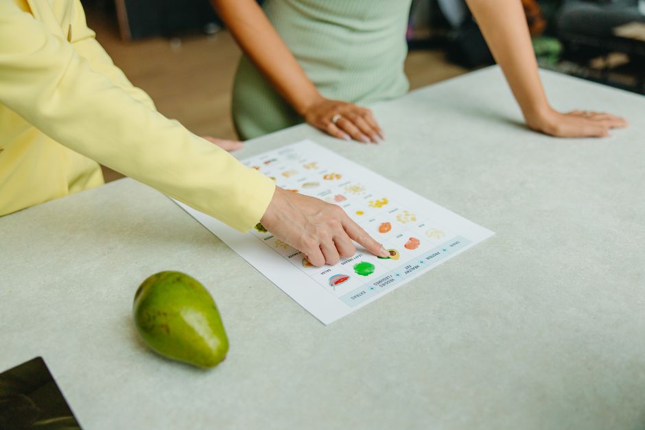 La pyramide alimentaire est-elle encore valide? Two adults discussing food options with a chart, highlighting healthy nutrition indoors.