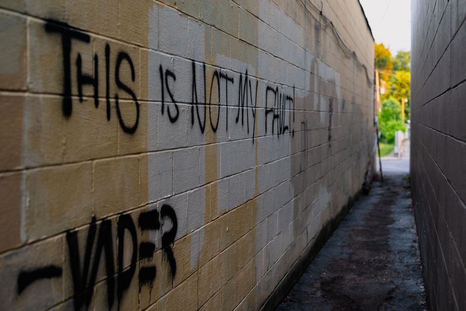 Les tremblements de terre peuvent-ils être provoqués par l’homme? Urban alleyway with graffiti saying "This is not my fault." Dimly lit passage with text art.