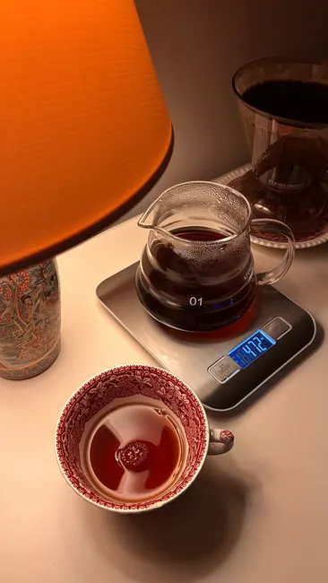 Warm indoor scene with a cup of tea, digital scale, and lamp.