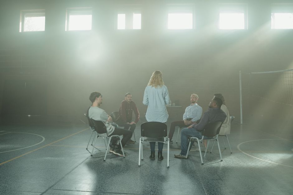 L’hypnose peut-elle vraiment aider à arrêter de fumer? A group therapy session with diverse adults seated in a sunlit room.