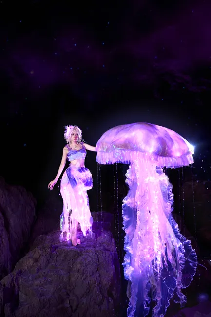 A mystical scene featuring a woman with a glowing jellyfish at night, set against a starry backdrop.